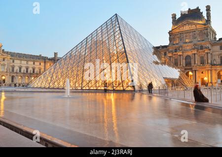 Parigi, Francia - 18 novembre 2021: Vista del Museo del Louvre con la Piramide al crepuscolo. Questa è una delle destinazioni di viaggio più popolari di Fran Foto Stock