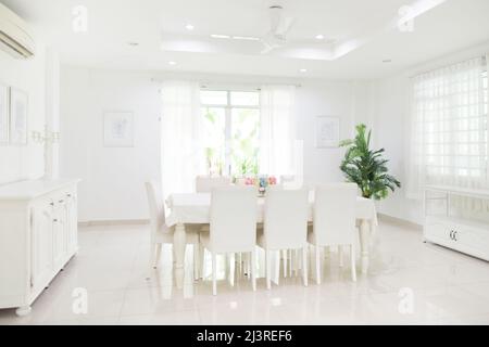 Interni domestici. Design della sala da pranzo. Tavolo e sedie in casa bianca soleggiata. Angolo cottura per la colazione in appartamento per famiglie. Foto Stock