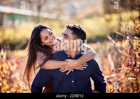 Dolce cavalcare con il mio amore. Scatto di una giovane coppia che ha una data in un'azienda vinicola. Foto Stock