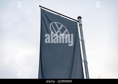 Volkswagen AG logo su una bandiera alta appesa molto alto. Emblema VW su un banner tessile blu scuro che si muove nel vento. Industria automobilistica in Germania. Foto Stock