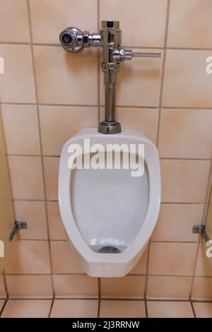 Orinatoio da uomo contro piastrelle rosa nei bagni pubblici. Foto Stock