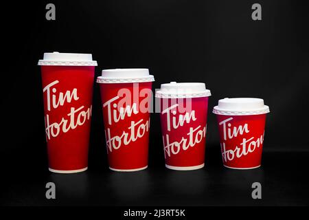 Calgary, Alberta, Canada. Aprile 9, 2022. Tazzine di caffè Tim Hortons di diverse dimensioni su sfondo nero Foto Stock