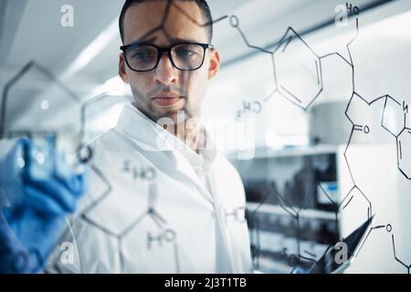 Gli scienziati lo mantengono super intelligente. Scatto di un giovane scienziato che risolve le equazioni su uno schermo di vetro in un laboratorio. Foto Stock