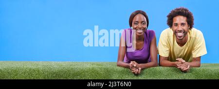 Semplicemente rilassarsi insieme. Una giovane coppia africana che giace insieme sull'erba. Foto Stock