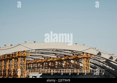 Ponte cittadino incompiuto: Telai in metallo giallo che sostengono la struttura ad arco Foto Stock