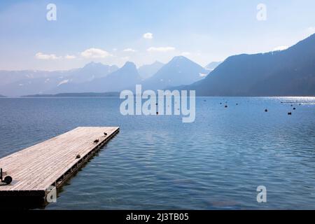 Vista panoramica di un lago australiano con molo in legno e catena montuosa sullo sfondo. Salzkammergut Austria superiore Foto Stock