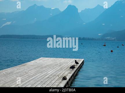 Vista panoramica di un lago australiano con molo in legno e catena montuosa sullo sfondo. Salzkammergut Austria superiore Foto Stock