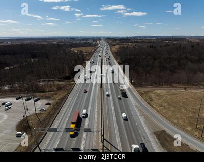 Un'alta vista aerea sopra una trafficata autostrada a più corsie interstate in una giornata poco nuvolosa e soleggiata. Foto Stock