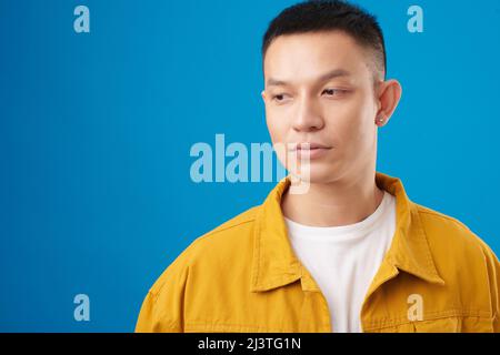 Ritratto del giovane vietnamita pensivo in giacca denim, isolato su blu Foto Stock