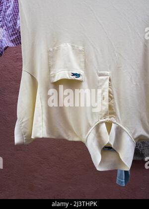 Camicia a polo umida Lacoste appesa all'esterno sull'asciugatura dei vestiti Foto Stock