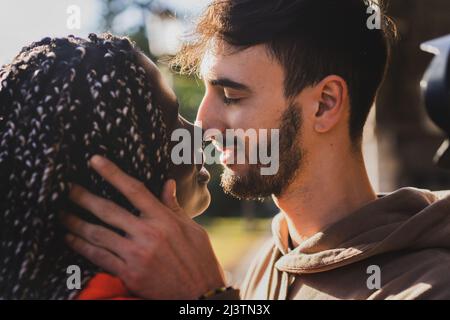 Fidanzato coppia biraciale di generazione z giovani baciare nel parco - primo piano colpo Foto Stock