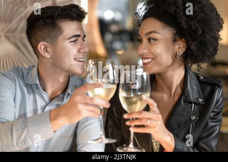 Abbinate un bicchiere di vino frizzante in un elegante ristorante. Romantico ragazzo e ragazza tostatura con vino bianco. Foto Stock