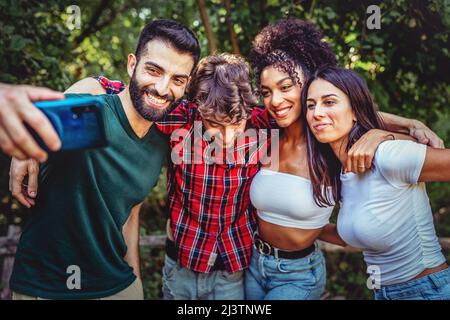 Un gruppo biraciale di migliori amici scherza insieme prendendo selfie in campagna Foto Stock