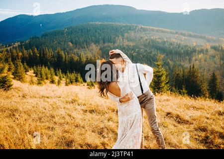 Felice splendida sposa ed elegante sposo correre e divertirsi, boho coppia di nozze, cerimonia di lusso in montagna con vista incredibile Foto Stock