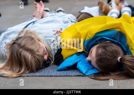 I manifestanti che hanno fatto un moriboire, facendo riferimento ai civili ucraini uccisi in città come Bucha durante la guerra con la Russia. Due giovani femmine 'papà' Foto Stock