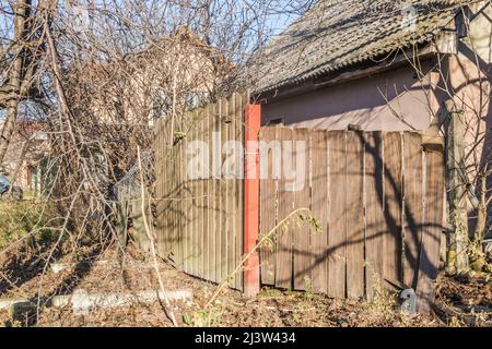 Cancello in legno abbandonato, vecchie case dilapidate alla periferia della città. Foto Stock