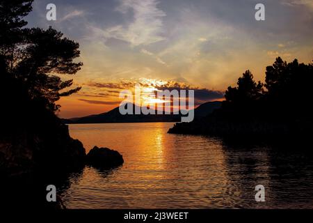 Paesaggio incredibile. Tramonto in mare su sfondo di montagne e barca Foto Stock