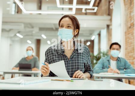 Studentessa femminile che ascolta attentamente l'insegnante all'università Foto Stock