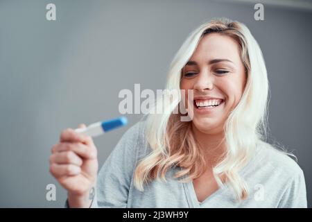 Non poteva essere più felice dei risultati. Scatto di una giovane donna che guarda i risultati del suo test di gravidanza a casa. Foto Stock