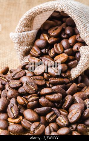 Il sacco di iuta con chicchi di caffè su tavola di legno. Foto Stock