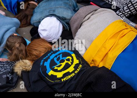I manifestanti che hanno fatto un moriboire, facendo riferimento ai civili ucraini uccisi in città come Bucha durante la guerra con la Russia. Bandiera Ucraina Foto Stock