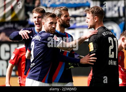 Kiel, Germania. 10th Apr 2022. Calcio: 2nd Bundesliga, Holstein Kiel - Hamburger SV, Matchday 29, Holstein Stadium. Phil Neumann di Kiel (l-r), Marco Komenda di Kiel e Stefan Thesker di Kiel celebrano il portiere di Kiel Thomas Dähne per una palla in mano. Credit: Axel Heimken/dpa - NOTA IMPORTANTE: In conformità con i requisiti della DFL Deutsche Fußball Liga e della DFB Deutscher Fußball-Bund, è vietato utilizzare o utilizzare fotografie scattate nello stadio e/o della partita sotto forma di immagini di sequenza e/o serie di foto video-simili./dpa/Alamy Live News Foto Stock