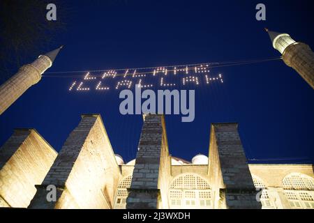 ISTANBUL, TURCHIA - 09 APRILE 2022: Mahya tra la Moschea di Hagia Sophi. Mahya è l'iscrizione illuminata posta tra i due minareti della moschea du Foto Stock