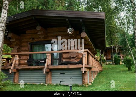 Casa di montagna in legno costruita con tronchi di legno. Bella casa di tronchi con portico, patio e vialetto in tranquillo paesaggio forestale Foto Stock