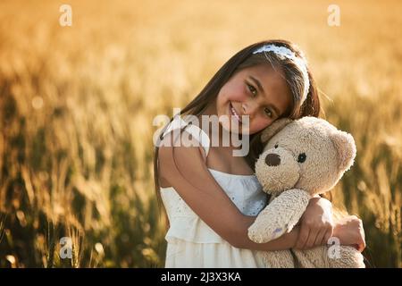 Trova il sole in ogni giorno. Ritratto di una ragazza carina che gioca con il suo orsacchiotto in un campo di mais. Foto Stock