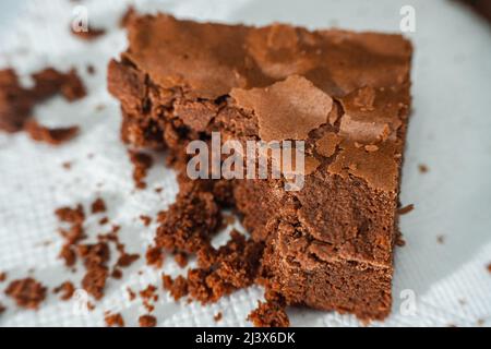 Un cubetto di brownie al cioccolato su un piatto bianco su un tavolo di marmo. Foto Stock