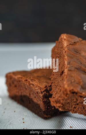 Un cubetto di brownie al cioccolato su un piatto bianco su un tavolo di marmo. Primo piano. Orientamento verticale. Foto Stock