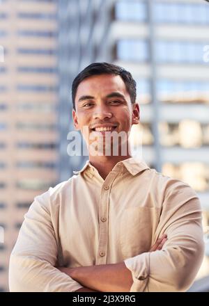 Un giovane e attraente uomo asiatico sorride per il ritratto di fronte agli edifici della città Foto Stock
