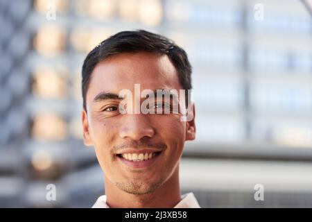 Un attraente uomo del Sud Est Asiatico sorride per un ritratto fuori dall'edificio cittadino Foto Stock