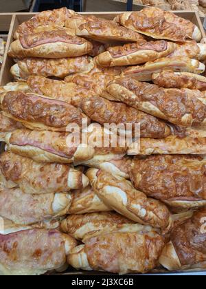 Pane fresco di rohlik ceco bianco con pancetta e formaggio fuso sulla parte superiore, chiamato inglese rohlik in panetteria o negozio di alimentari. Rotolo di pane alla griglia. Primo piano di esposizione in supermercato Foto Stock