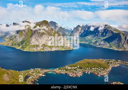 Cime frastagliate di nuvole oltre la spettacolare città di Reine vista dalla cima di Reinebringen nelle isole Lofoten occidentali Foto Stock