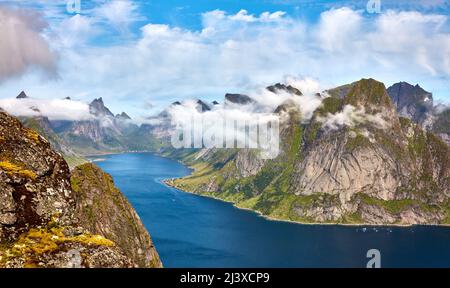 Cloud frastagliate inghirlandato picchi intorno al Reinefjord dalla cima del Reinebringen in western Isole Lofoten Foto Stock