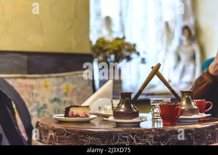 Caffè in turco su un tavolo con un pezzo di torta al formaggio. Concentratevi sul Turco. Foto Stock
