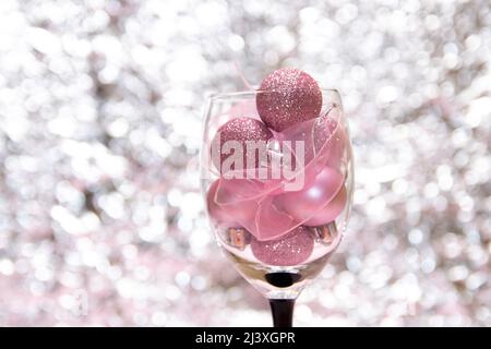 Palline rosa in un bicchiere su sfondo bokeh lucido sfocato. Foto Stock