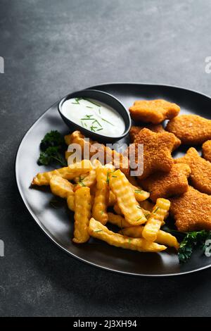 Fish chips fast food britannico. Bastoncini di pesce con patatine fritte su piatto nero su sfondo nero. Tradizionale britannico autentico Street food o. Foto Stock