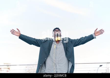 uomo sorridente braccia alzate fino al cielo blu, celebrando la libertà. Emozioni umane positive, espressione facciale sensazione di vita percezione successo, pace della mente c Foto Stock