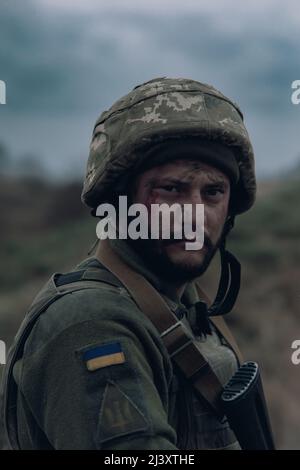 Ritratto del soldato ucraino in casco con fucile d'assalto kalashnikov. Concetto di invasione militare russa in Ucraina. Guerra in Ucraina e in Europa. Foto Stock