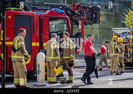 Gruppo di vigili del fuoco accanto ad un motore antincendio che ha messo fuori un incendio al museo "We are curious" di Bristol Harbourside, Regno Unito, il 9 aprile 2022 Foto Stock