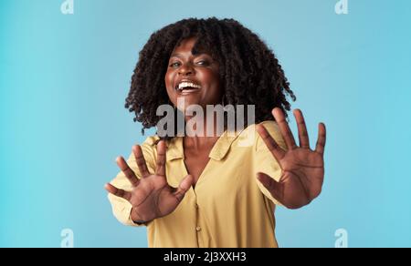 WOah troppe informazioni. Studio girato di una giovane donna attraente che tiene fuori le sue braccia su uno sfondo blu. Foto Stock