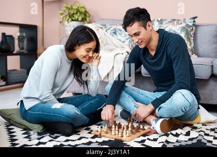 Sconfiggi il blues di blocco con un divertente gioco da tavolo. Scatto di una giovane coppia che gioca una partita di scacchi a casa. Foto Stock