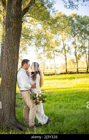 giovane coppia sposa e sposo stanno camminando su una passeggiata nella foresta. concetto di giorno di nozze. giorno romantico. ritratto di sposi novelli nell'amore. Foto Stock