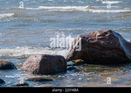 Mar Baltico, Golfo di riga, rocce in acqua, primavera. Onda spruzzando sopra le rocce. Foto Stock