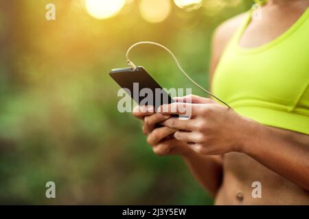 Tieni traccia di ogni corsa. Scatto corto di una giovane donna usando il suo telefono mentre fuori per una corsa. Foto Stock
