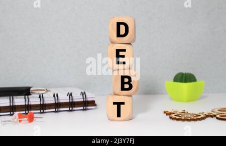 Imprenditore rimuove i blocchi di legno con la parola debito. Riduzione o la ristrutturazione del debito. Annuncio di fallimento. Il rifiuto di pagare i debiti o crediti e i Foto Stock