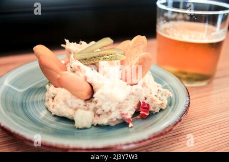 Tapa di insalate russe accanto alla birra fredda su un banco bar spagnolo Foto Stock