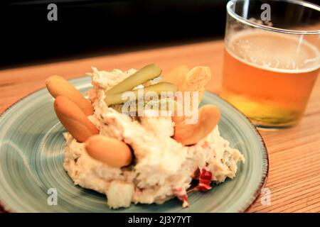 Tapa di insalate russe accanto alla birra fredda su un banco bar spagnolo Foto Stock